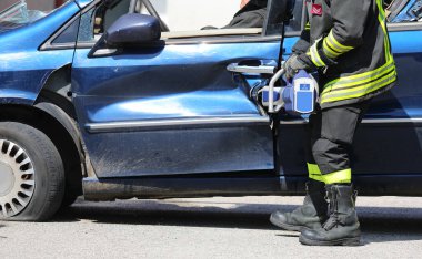 İtfaiyeci, hurdaya dönmüş bir arabanın kapısını güçlü bir hidrolik kesici olan Jaws of Life ile açıyor.