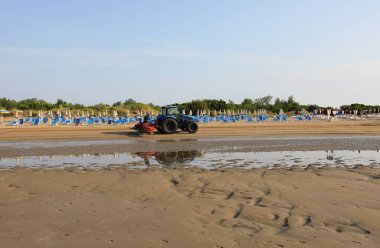 Yazın banyocular gelmeden önce arkada plaj temizliği için büyük bir metal tırmıkla donatılmış bir kamyon.