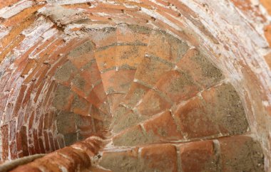 Narrow spiral staircase in an old tower made of stones and bricks clipart