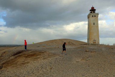 Hjorring, JUT, Denmark - August 25, 2024: Rubjerg Knude Lighthouse in Danish language Rubjerg Knude Fyr on the Jutland peninsula surrounded by sand and people clipart