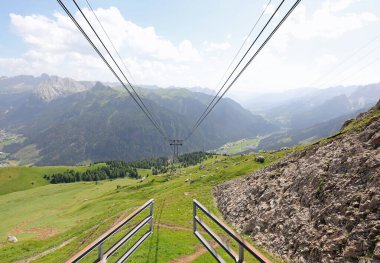 Vadi zemininden yükselen teleferiğin en üst istasyonu güçlü çelik kabloları ve çayırdaki kulesiyle