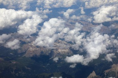 Uçan ticari bir uçaktan dağların ve beyaz bulutların havadan görünüşü