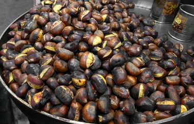 Sonbaharda sokak yemekleri satan bir yerde büyük metal bir tavada pişmiş kestane.