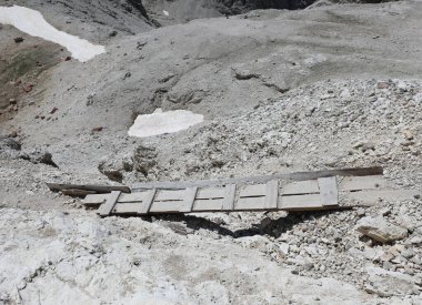 Çok eski, çürük ve dengesiz ahşap bir köprü, bir dağ yolunda çakıllı vadiyi geçmek için.