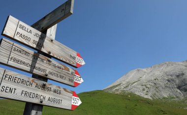 wooden arrows with directions to alpine refuges and mountains in Italian without people in summer without people clipart