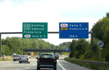 Kuzeyde Danimarka 'da otoyol işaretleri ve aşağıda hız yapan büyük şehir ve arabaların yönleri