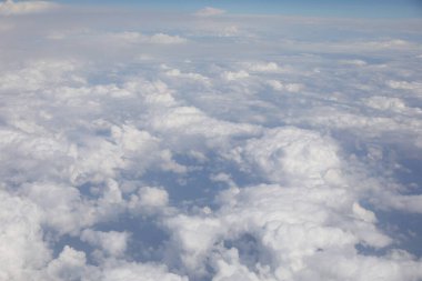 Bir uçaktaki kıtalararası uçuş sırasında yukarıdan görünen beyaz bulutlar.