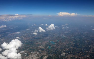 Yolları, evleri ve ekili tarlaları olan düz ve beyaz bulutların uçaktan görünüşü