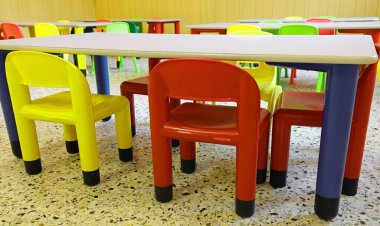 Anaokulunda çocuklar olmadan öğretmenlik yapmak için sınıfın içinde renkli küçük plastik sandalyeler.