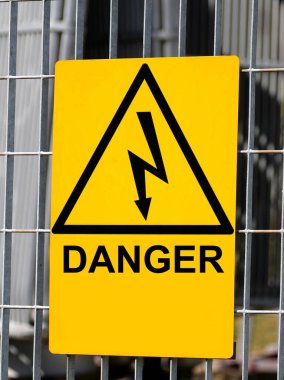 Yüksek voltajlı elektrik santralinin çitinde yıldırım sembolü ve üçgeniyle 