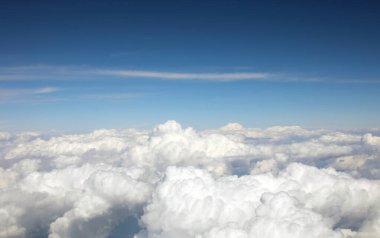 Beyaz kabarık bulutların ve mavi gökyüzünün anlamlı görüntüsü bir uçaktan uçarken görüldü.