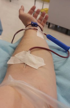 İğne saplanmış kişinin kolu ve kanla dolu plastik tüp.