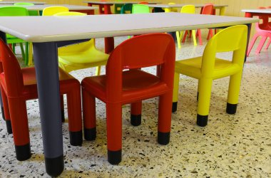 Anaokulunda çocuksuz bir sürü renkli plastik sandalye var.