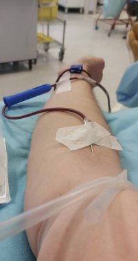 İğne batırılmış bir insan kolu ve hastane sedyesinde kanla dolu bir plastik tüp.