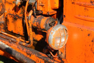 Geçen yüzyıldan kalma eski bir turuncu traktörün ön farının yakın çekimi.