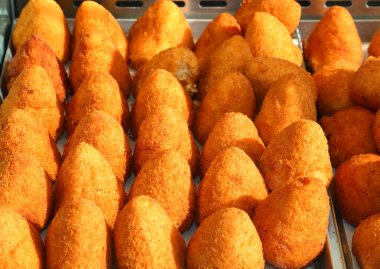 many fried rice balls called arancini or arancine, typical of the island of Sicily in southern Italy on sale at local market clipart