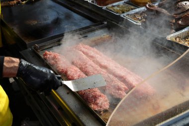 Lezzetli sandviçler için uzun domuz sosisleri pişirirken bir sokak yemeği standında yemek eldiveni.