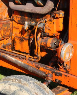 Farı ve motor parçası olan eski bir turuncu tarım traktörünün ayrıntıları