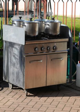 Mutfakta ocağı ocağı ve ocağı ısıtan dört tencere yemek hazırlıkları sırasında buharlaşıyor.