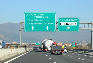 Birçok araç ve kamyon otobanda hız yapıyor ve İtalya 'nın ünlü şehirleri Floransa Bologna Pisa Genoa' ya giden yol işaretleri var.