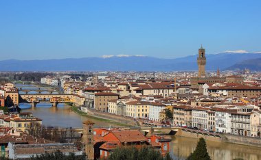 İtalya 'nın Floransa şehrinin panoramik manzarası. Solunda Ponte Vecchio ve arkasında karlı Apennine dağları olan Palazzo della Signoria Kulesi.