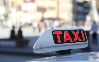 Şehirdeki büyük kırmızı metni olan bir taksinin üstündeki ışıklı tabela.