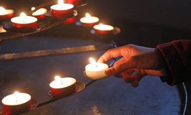 Worshi 'nin yerine dua etmek için mum yakan genç bir kızın eli.