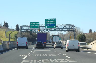İtalya otobanında İtalyan şehir isimlerini gösteren bir tabela. İtalya 'da arabaları ve kamyonetleri olan.