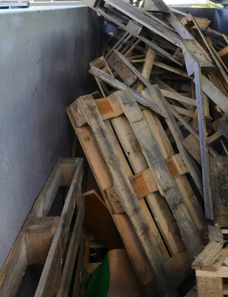 Çöp konteynırında kullanılmış paletler ve odun parçaları ayrı bir atık toplayıcılığını gerçekleştirir.