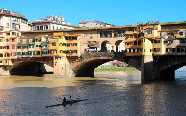 İtalya 'nın FLORENCE şehrinde PONTE VECCHIO adında ünlü bir köprü ve mavi gökyüzü ve suda bir kano ile Arno Nehri.
