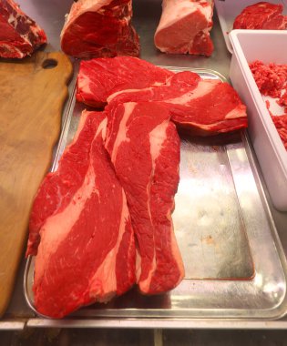 Kasap dükkanının soğuk tezgahında satılık yağlı kırmızı et var.