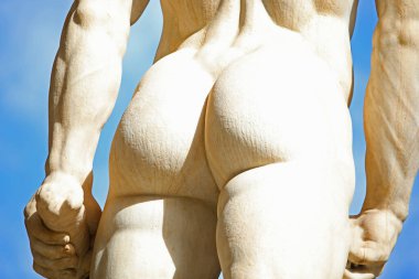 Heykelin çok sıkı çıplak kalçaları ve kaslı kolları arkadan görülüyor.