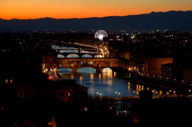 Ponte Vecchio gece İtalya 'da Floransa' da ve ARno nehrinin suları ve dönme dolap üzerinde yansıyor.