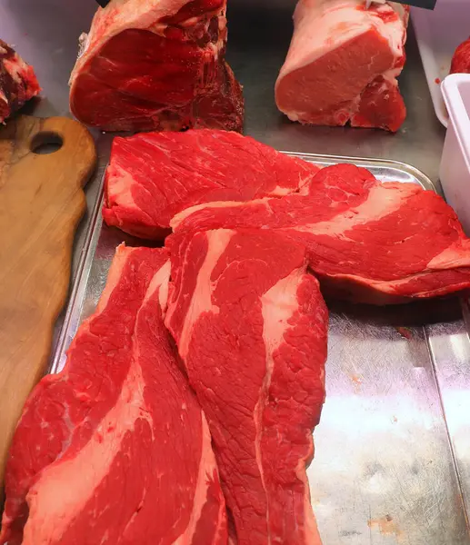 Kasaptaki kasapta satılık büyük kırmızı et parçaları var.