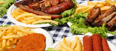 Köy festivali masasında kareli masa örtüsü ve doğranmış sosisli tabaklar.