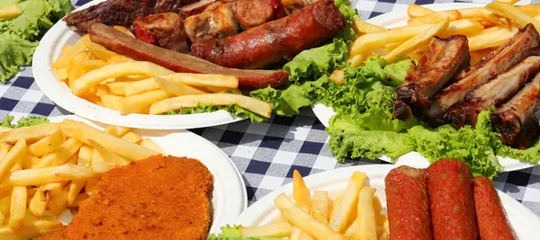 Köy festivali masasında kareli masa örtüsü ve doğranmış sosisli tabaklar.