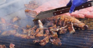 Lokantanın sıcak ızgara etini pişiren lateks mavi eldivenli aşçı.