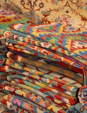 Halı dükkanında satılık geometrik tasarımları ve şekilleri olan renkli halı yığını.