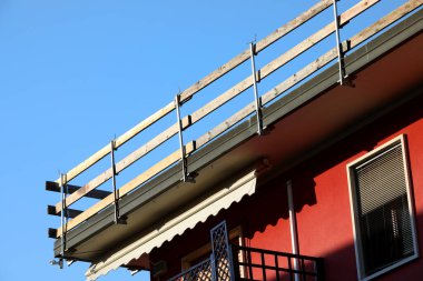 Dayanıklı koruyucu bariyerin ahşap kalasları işçilerin güvenliği için sıkıca yerleştirildi. Dairenin çatısında bakım sırasında insanlar olmadan düşmesinler diye.