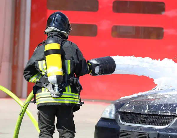 İtfaiye hortumu, köpük ve trafik kazasından sonra kırık bir arabayla itfaiyeci.