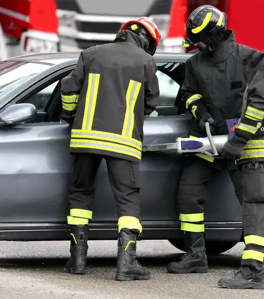 İki itfaiyeci trafik kazasından sonra arabanın kapısını açmak için Jaws of Life adında bir hidrolik retraktör kullanıyor.