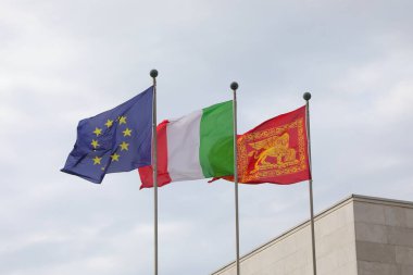 Venezia, VE, İtalya - 6 Mayıs 2025: Sarı yıldızlı Üç Büyük Bayraklı Avrupa Birliği Mavisi ve İtalyan ve Venedik Bölgesi Bayraklı Kanatlı Aslan