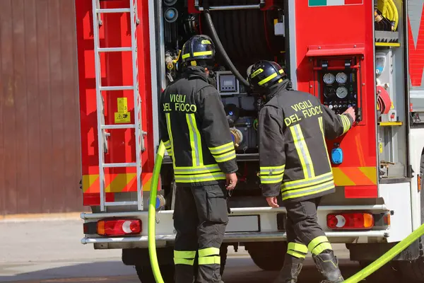 Vicenza, VI, İtalya - 15 Mayıs 2025: kırmızı itfaiye kamyonu ve iki italyan itfaiyeci.