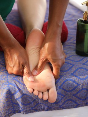 Ayak tabanına, ayak refleksolojisini takip eden bölgelere masaj yapmak için güçlü bir akupres uygulayan masöz.