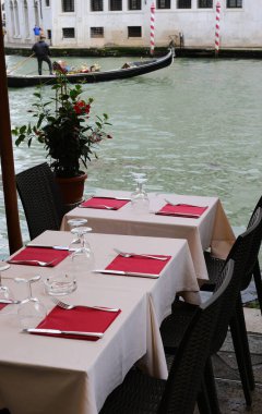 Venedik 'teki Büyük Kanal' ın kıyısındaki açık hava restoranının masasını ve arka plandaki Rialto Köprüsü 'nü ayarla.