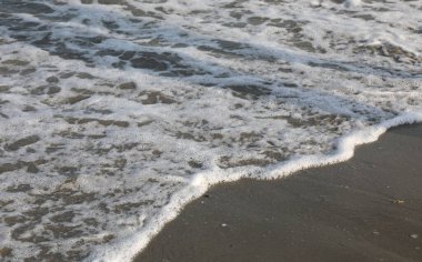 Kumlu kıyı şeridindeki deniz köpüğü özel metin için ideal bir arkaplan