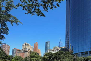 Manhattan 'ın gökdelenleri New York şehrinin batarya parkından mavi gökyüzüne doğru yükseliyor.