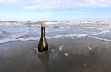 Deniz kıyısında içinde gizli bir mesaj olan cam şişe.