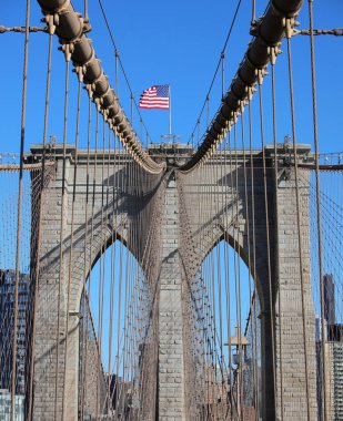Brooklyn Köprüsü 'nün tepesinde Büyük Amerikan Bayrağı ve birçok çelik kabloyla New York şehri