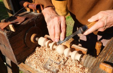 Usta zanaatkârın parmakları vintage dönüş makinesinde kereste şekillendiriyor.